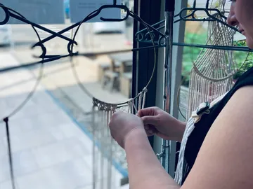 A person creates a decorative macrame indoors.