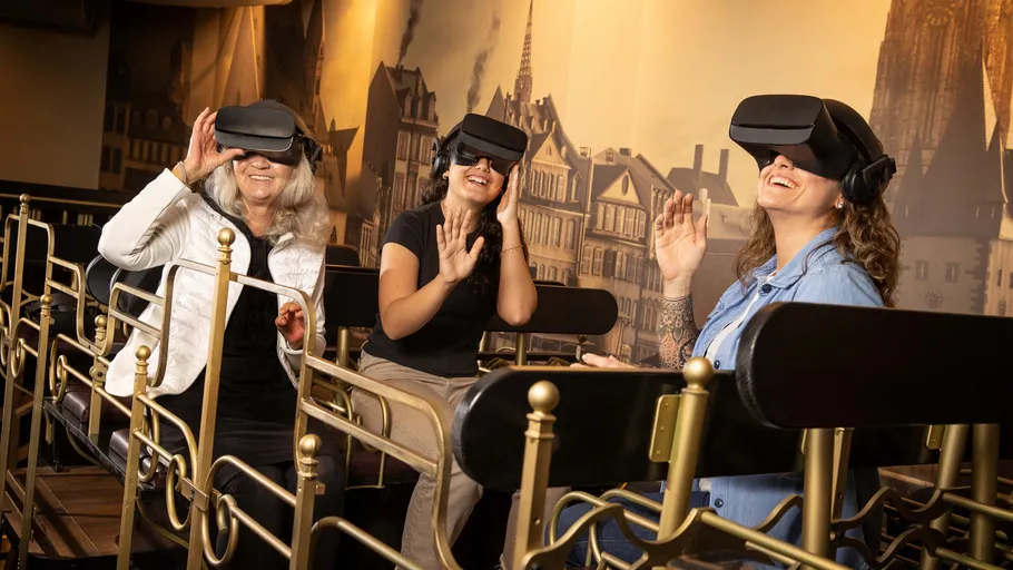 Three women using VR headsets in theme park.