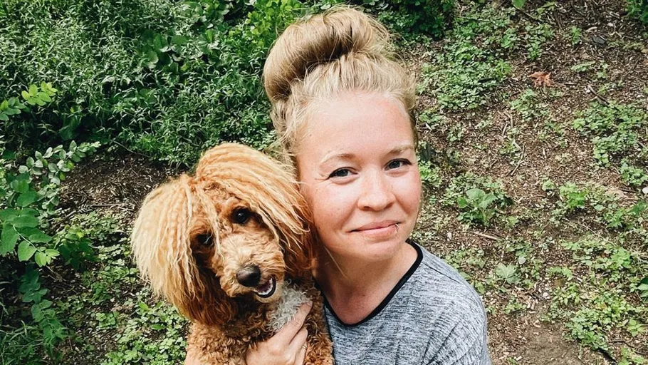 Frau umarmt einen Hund im Garten.