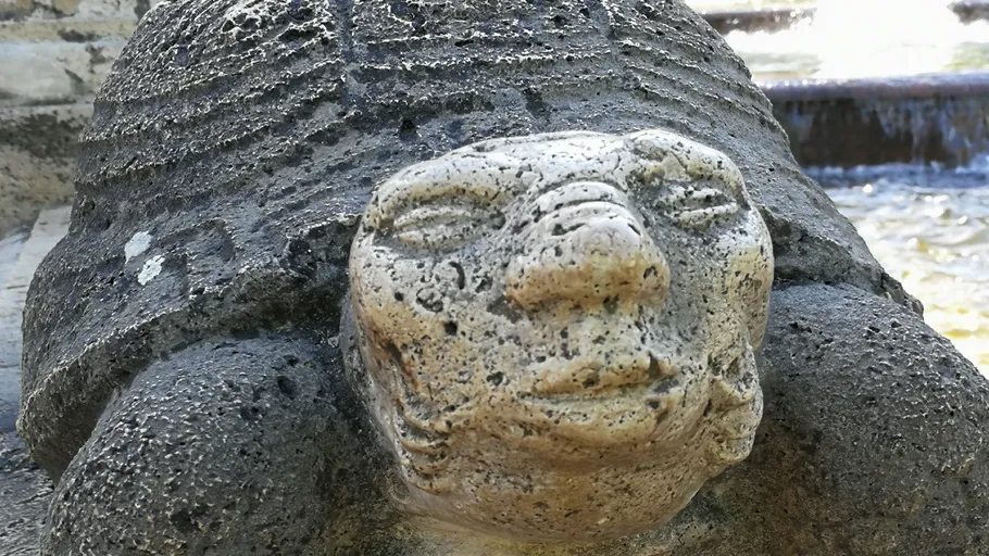 Steinschildkrötenskulptur mit menschlichem Gesicht.
