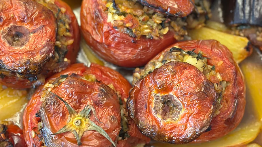 Stuffed tomatoes with rice and herbs in tray.