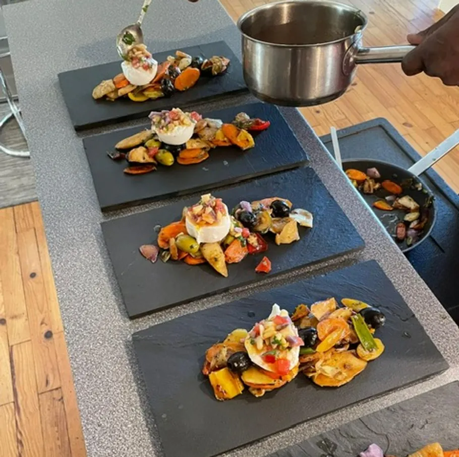 Chef plating gourmet dishes on slate plates.