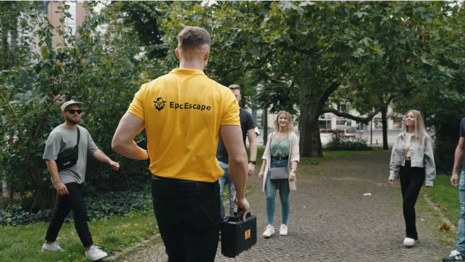 Mann im gelben Hemd mit Koffer, Gruppe nähert sich.