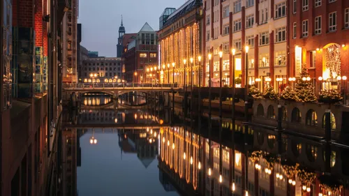 Canal reflecting illuminated buildings at dusk.