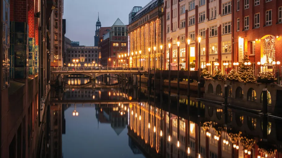 Kanal spiegelt beleuchtete Gebäude bei Dämmerung.