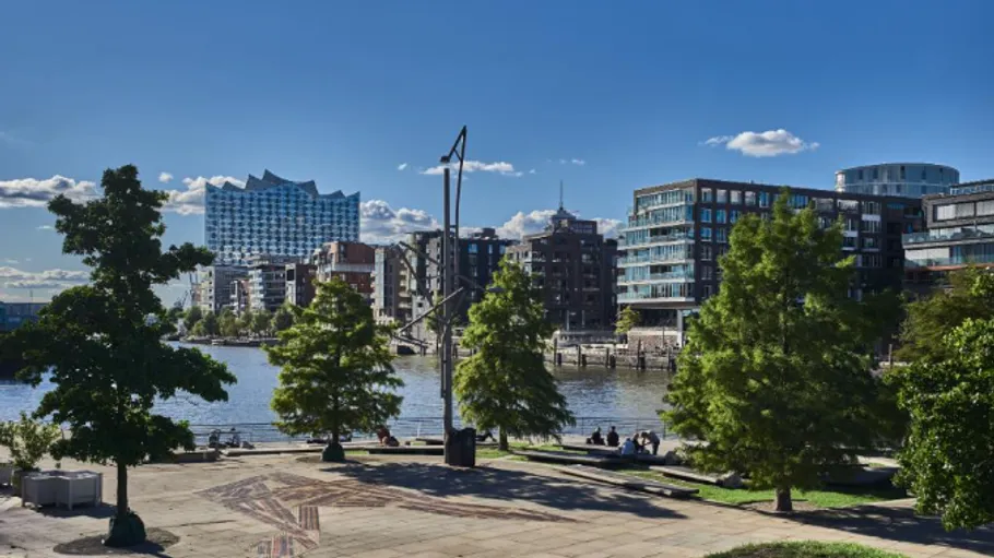 Modern buildings by river with blue sky.
