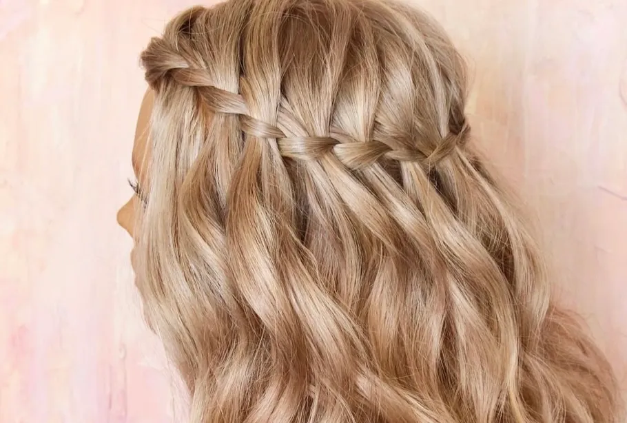 Blondes Haar mit Wasserfallzopf, rosa Hintergrund.