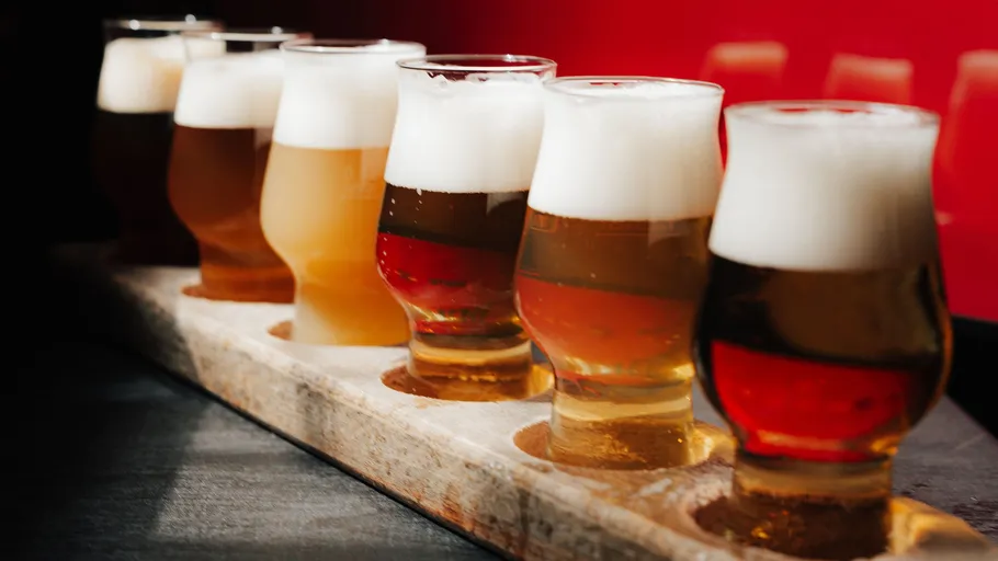 Biergläser auf Holzbrette, roter Hintergrund.