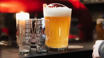 Pitcher of beer and glasses on bar.