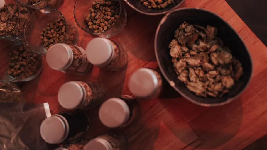 Jars and bowls of hops on wood table.