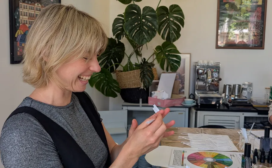 Smiling woman holding papers in a kitchen.