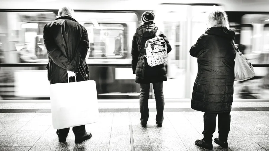Drei Personen warten auf U-Bahn-Steig.