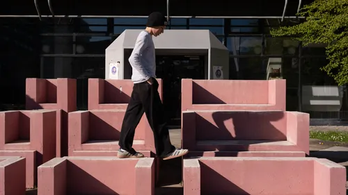 Person walking on pink concrete blocks outside.