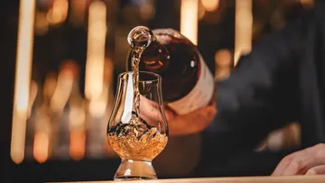 Whiskey being poured into glass on bar.