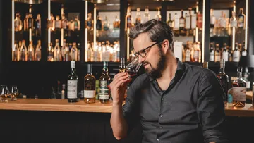 Mann riecht an Whisky in einer Bar.