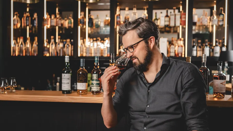Man smelling whisky in a bar setting.