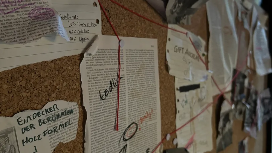 Corkboard with papers, notes, and red strings.