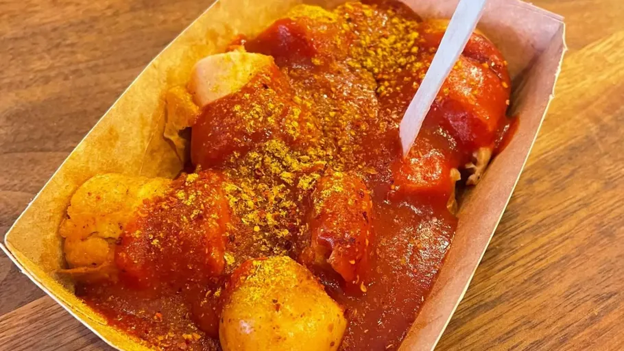 Currywurst mit Sauce auf Holztisch.
