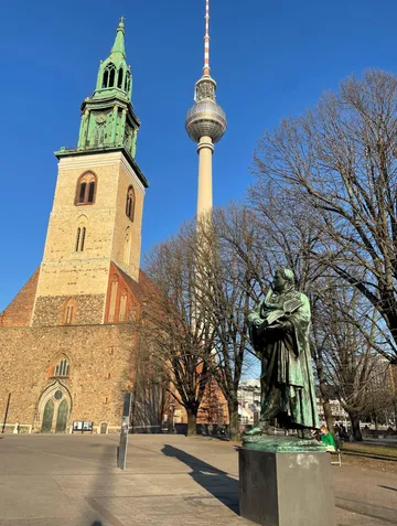 Church, statue, and tower in city square.