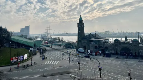 Clock tower by waterfront with cloudy sky.