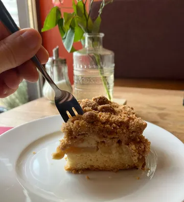 Person eating crumb cake inside cafe.