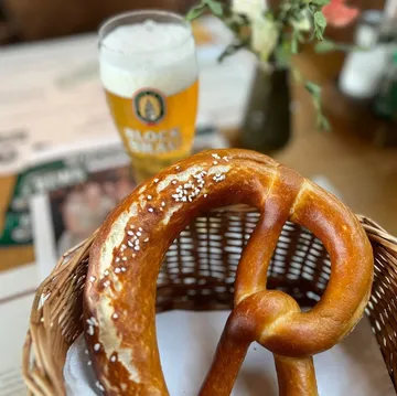 Pretzel in basket with beer glass nearby.