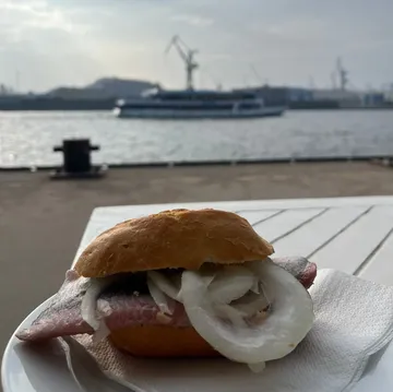 Fish sandwich on table by waterfront.