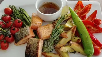 Grilled salmon with vegetables and sauce on plate.
