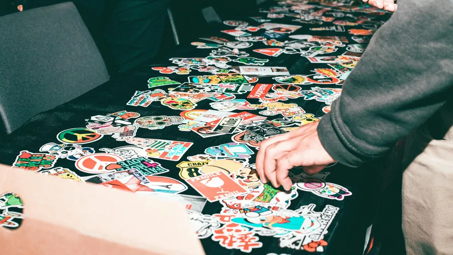 Person browsing colorful stickers on table.