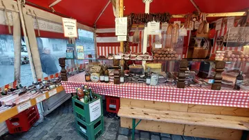 Marktstand mit Fleischwaren und Flaschengetränken ausgestellt.