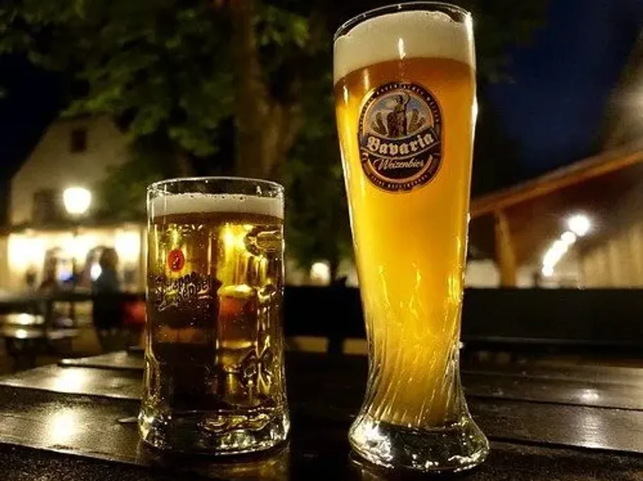 Zwei Biergläser auf Außentisch bei Nacht.