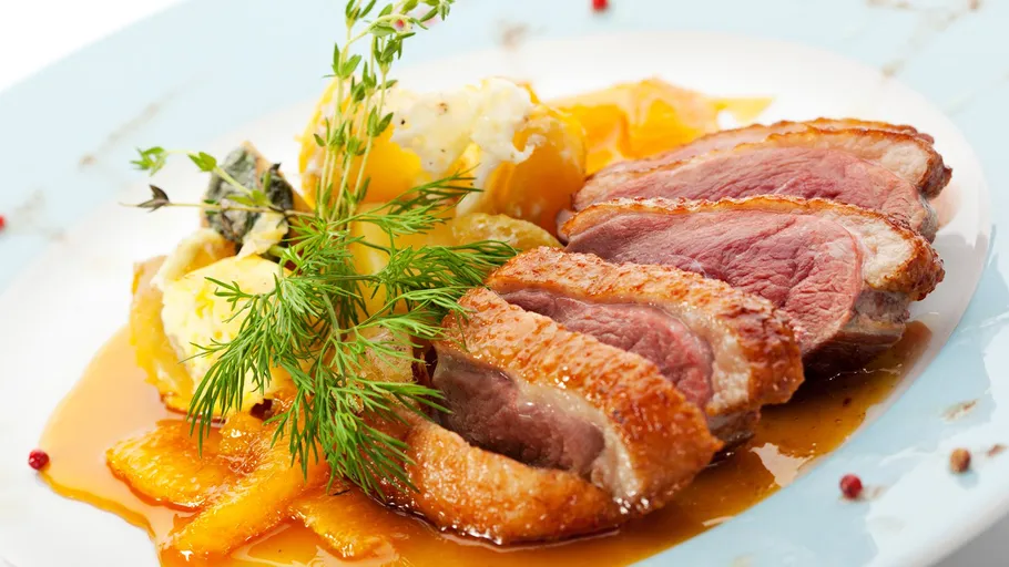 Gebackene Entenbrust mit Sauce und Garnitur.