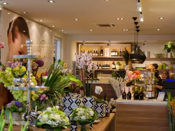 Blumenladen mit Blumen, Verkaufsaktivität und Weinflaschenregal.