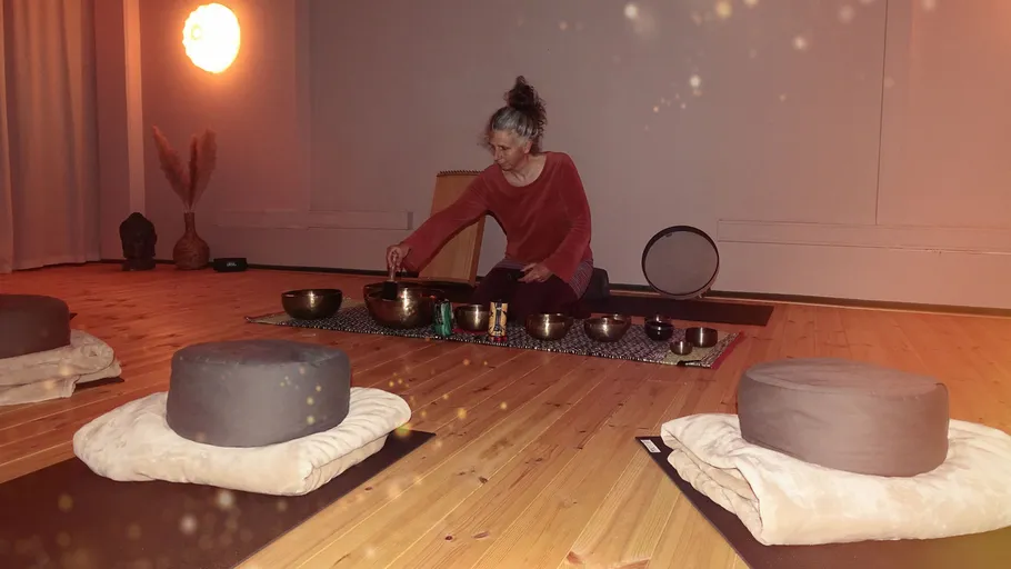 Person playing singing bowls in a serene room.