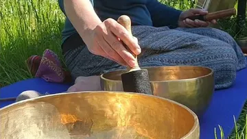 Person spielt Klangschalen im Freien.