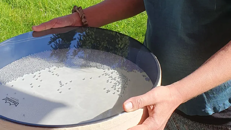 Person holding circular object with beads outdoors.