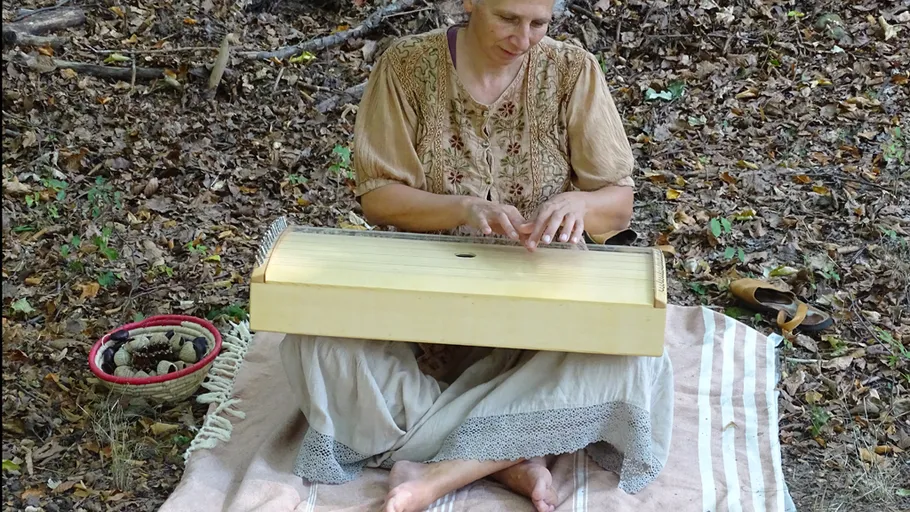 Woman playing instrument in forest setting.