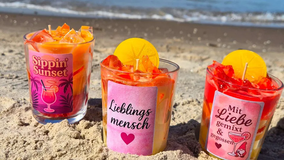 Kerzen am Sandstrand mit Meer im Hintergrund.