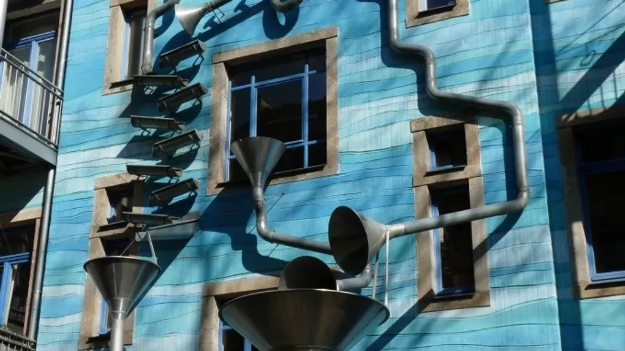 Blaues Gebäude mit künstlerischen Abflussrohren.
