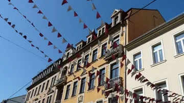 Bunte Fahnen hängen über Wohnhäusern.