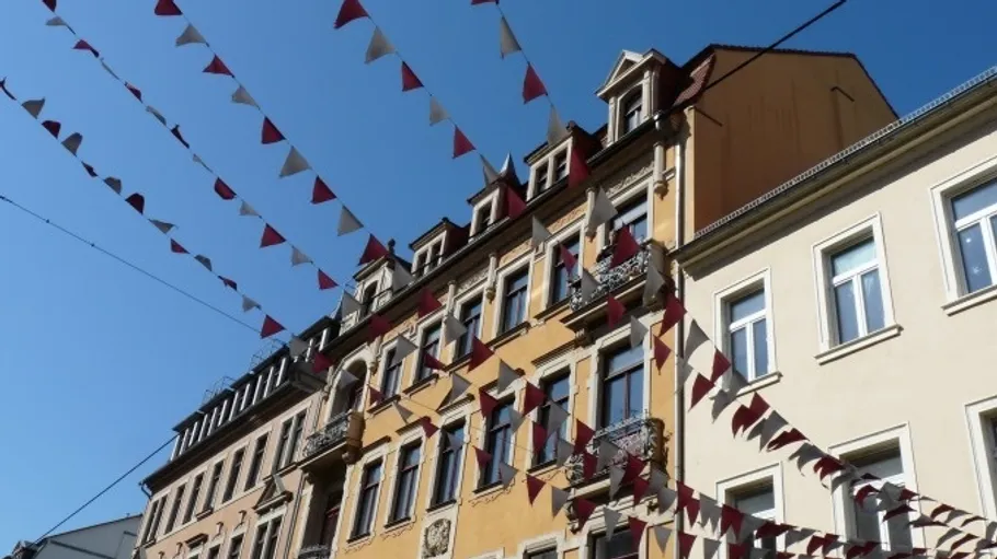 Bunte Fahnen hängen über Wohnhäusern.