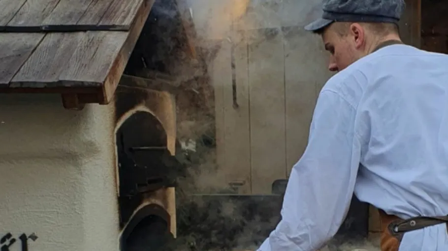 Man in cap working at a smokehouse.