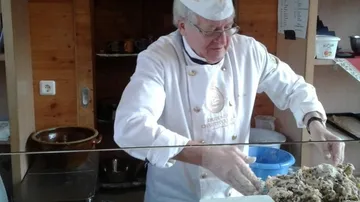 Bäcker bereitet Teig in rustikaler Küche zu.