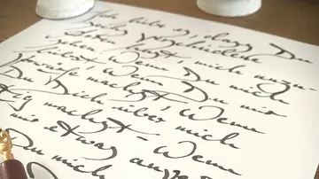 Handwritten letter on a table, ink pen nearby.