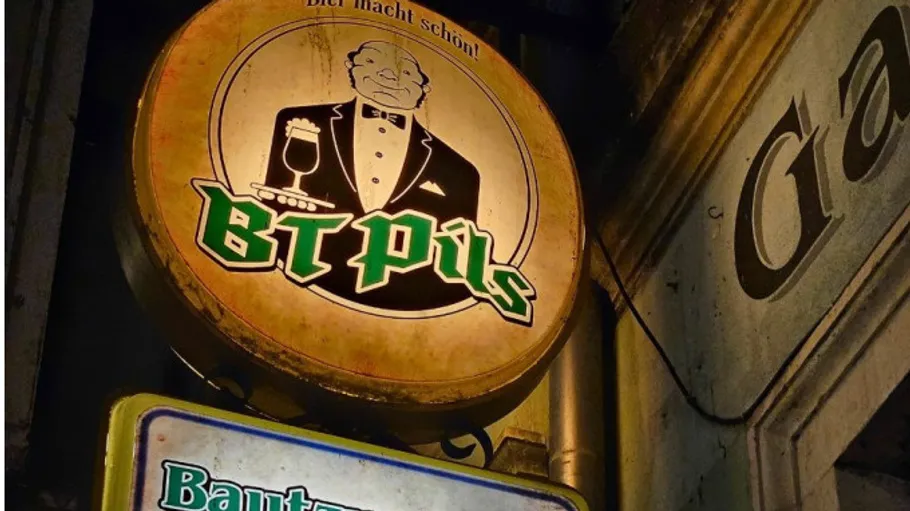 Kneipenschild mit Kellner, der Bier hält, draußen.