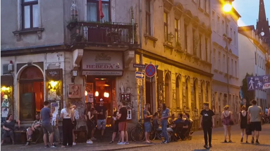Menschen versammeln sich abends vor einer Bar.