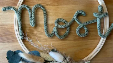 Woven word 'most' in embroidery hoop decor.