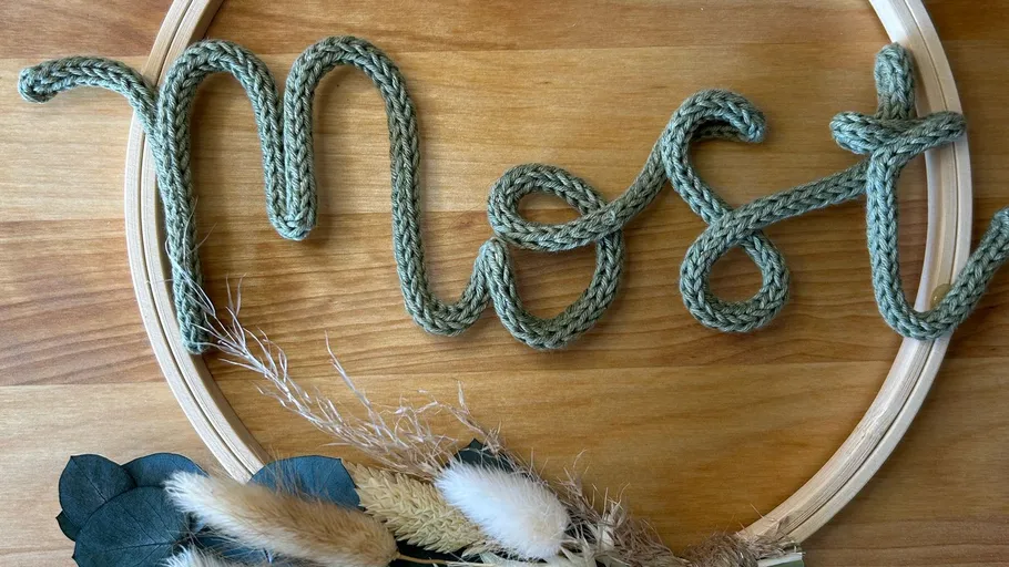Woven word 'most' in embroidery hoop decor.