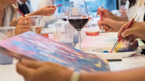People painting while holding drinks in a class.
