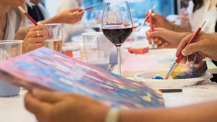 People painting while holding drinks in a class.